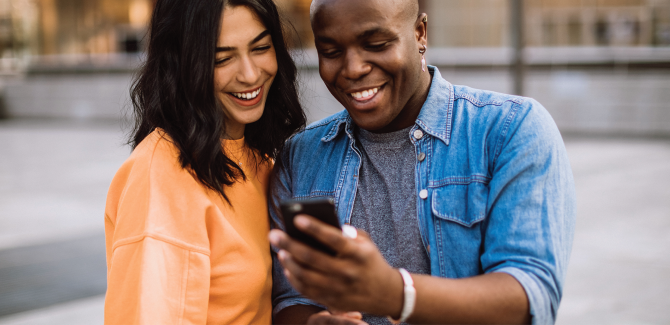 Two people looking at a phone and smiling