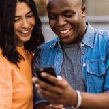 Two people looking at a phone and smiling